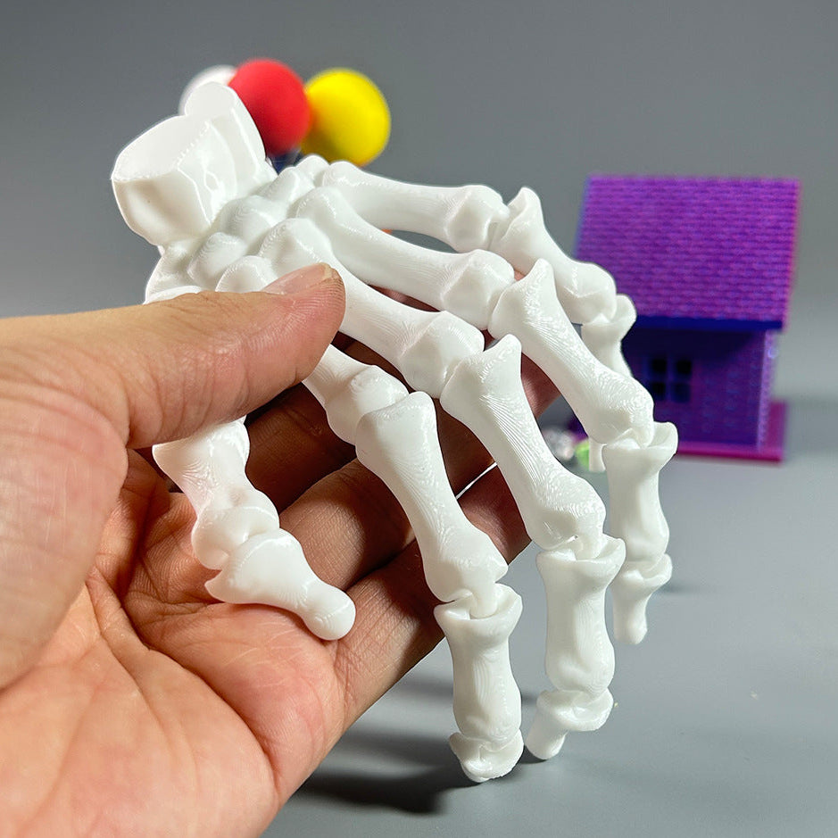 Hand holding a white 3D-printed skeleton model with colorful spheres on a gray background